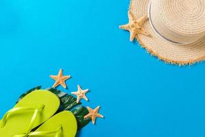 Beach accessories with straw hat and seashells on blue background top view with copy space photo