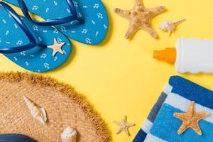 flip flops, straw hat, starfish, sunscreen bottle, body lotion spray on yellow background top view . flat lay summer beach sea accessories background, travel concept photo