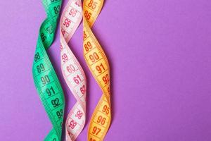 Close up of colorful measure tapes on purple background. Perfect female figure measurements concept photo