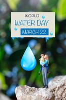 Miniature people mother holding son in the arms and words written on paper World Water Day photo