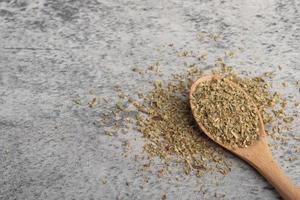 oregano in wooden spoon on gray background photo