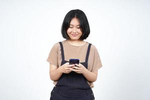 sosteniendo o usando un teléfono inteligente y una sonrisa de una hermosa mujer asiática aislada de fondo blanco foto