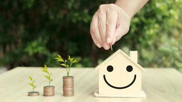 person putting coin on the piggybank on table, plant growing up on coin, business finance and saving money investment for buying a home,investing in real estate or property. photo