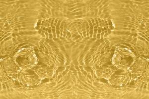 desenfoque borrosa transparente de color dorado claro textura de la superficie del agua tranquila con salpicaduras y burbujas. fondo de naturaleza abstracta de moda. ondas de agua a la luz del sol con cáusticos. agua amarilla que brilla foto
