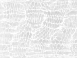 desenfoque borroso transparente color blanco claro agua tranquila textura superficial con salpicaduras y burbujas. fondo de naturaleza abstracta de moda. ondas de agua a la luz del sol con espacio de copia. brillo de agua blanca foto