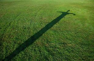 silhouette of man in cross shape on green grass photo