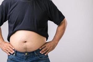 concepto de chequeo médico gente gorda mostrando su gran barriga. utilizado para el problema del hígado o el concepto de obesidad. foto de estudio en gris