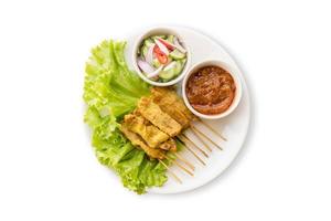 Pork Satay with Peanut Sauce and pickles which are cucumber slices and onions in vinegar. Isolated on white background photo