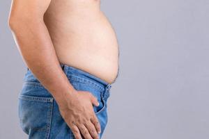 Fat man standing and show his tummy studio shot on grey background with copy space for text or design. Fat people and healthy concept photo