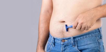 Portrait man using razor blade to cutting belly and body hair. Studio shot on grey photo