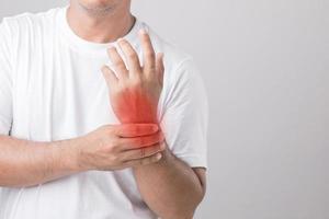 Close up man touching his Wrist and feeling a pain. Studio shot isolated on grey background with copy space for text photo