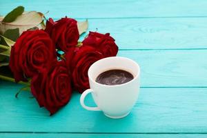 Cup of coffee with croissants and cookies and red roses on blue wooden background. Copy space. Mock up. Top view. Valentine mother day. photo