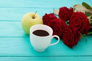 Cup of coffee on blue wooden table. Top view. Mock up. Hot drink. Selective focus. Red rouses bouquet. photo