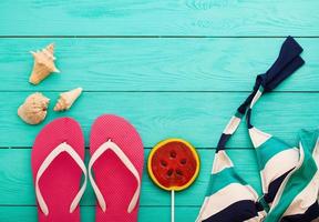 Summer accessories. Flip flops, sunglasses, towel, red cap and oranges on blue wooden background. copy space. photo