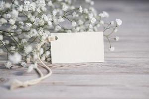 flores blancas y tarjeta blanca en blanco para texto. etiqueta de maqueta. tarjeta postal foto