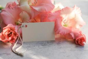 Bouquet of flowers and blank white card for text. Mockup tag. Postcard photo