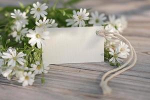 White flowers and blank white card for text. Mockup tag. Postcard photo
