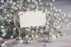 White flowers and blank white card for text. Mockup tag. Postcard photo