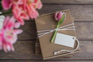 Mock up tag and kraft gift boxes decorated with flowers. Preparation of gifts for mother's day, birthday, women's holiday. Gift wrapping idea photo