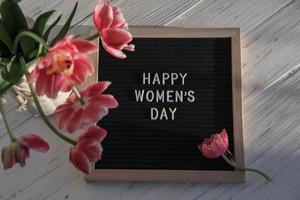 jarrón con tulipanes y tablero de letras con texto feliz día de la mujer foto