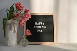 jarrón con tulipanes y tablero de letras con texto feliz día de la mujer foto