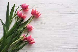 ramo de tulipanes rosas sobre un fondo blanco de madera. lugar para texto foto
