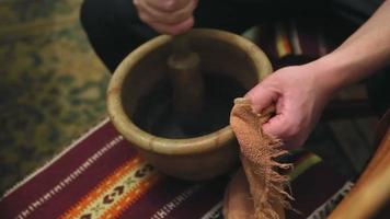 A man hands grind a poppy holding a wooden pestle and a old clay mortar - rustic style. Preparation for cooking traditional Ukrainian dish - Christmas Kutia. Festive porridge for the whole family. video