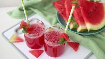 Healthy food - fresh delicious watermelon juice in two glasses with straws and watermelon slices on plate. Sweet gin punch in a table in bar. Summer refreshing smoothie drink. Easy alcoholic cocktail. video