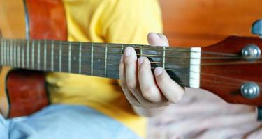 primer plano de las manos de un niño blanco sosteniendo acordes de guitarra foto