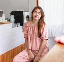 Fashion style portrait of a young beautiful person woman posing with long straight hair in a pink dress relaxing and smiling in the cafe. photo