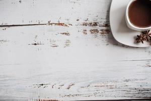 a Cup of coffee with cinnamon sticks on a light wooden background. space for text photo