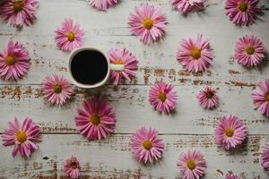 flores de jardín, taza de café de crisantemos y postal vacía sobre fondo de madera blanca con espacio de copia para su texto. plano, vista superior. foto