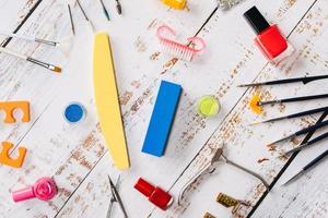 set of manicure tools and nail polishes on a white wooden background. photo