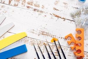 set of manicure tools and nail polishes on a white wooden background. with space for your text photo