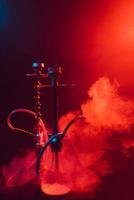 modern hookah, shisha on a smoky black background with colored lighting and smoke photo