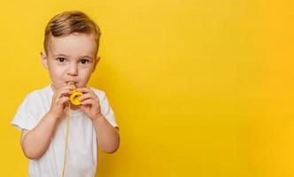 Portrait of a cute laughing little boy on a yellow background with a toy in his hands. Copy space. photo