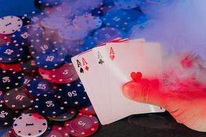 men's hands hold cards against the background of playing chips. there is smoke in the photo