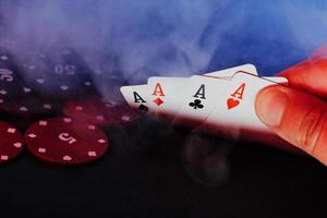 men's hands hold cards against the background of playing chips. there is smoke in the photo