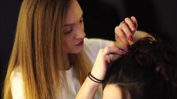 junge blonde Stylistin macht einer Frau im Haarstudio eine Frisur video