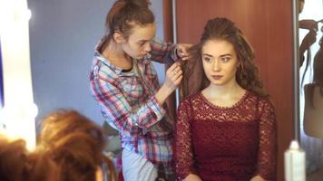 joven estilista rubia le hace peinado a una mujer en un estudio de cabello video