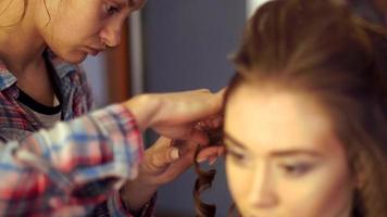 bionda stilista ragazza fa acconciatura per un' giovane donna nel capelli studio video