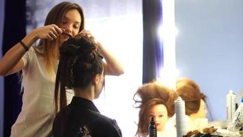 junge Stylistin macht einer Dame im Haarstudio eine Frisur video