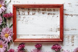 pink chrysanthemums are placed on a white wooden background with space for text and a frame photo