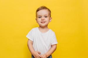 Smiling little boy on a yellow background. Copy space. photo