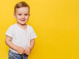 Portrait of a cute laughing little boy on a yellow background. Copy space. photo