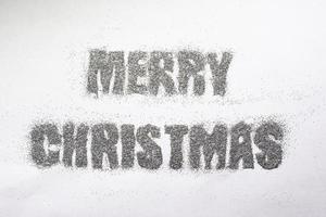 inscripción navideña en lentejuelas plateadas sobre fondo blanco foto