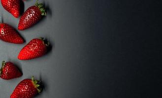 berries of ripe and juicy strawberries on a dark background. space for your text photo