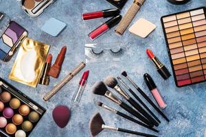 makeup brushes, decorative cosmetics, false eyelashes on a blue background. the view from the top photo