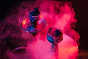 hookah bowl, shisha and coals close-up on a smoky black background with colored lighting photo