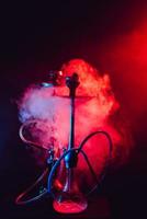 Fashionable hookah with a cloud of smoke on a black background with red and blue glow